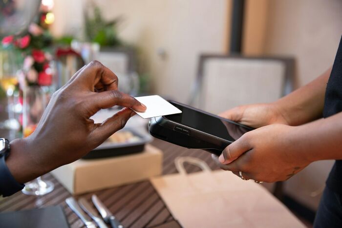 Hand holding a card over a payment terminal at a wedding reception, highlighting a wedding mishap during the transaction process.