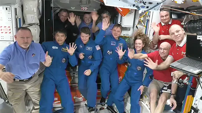 SpaceX Crew on ISS mission waving, ready to bring stranded NASA astronauts back home, celebrating teamwork in the station.
