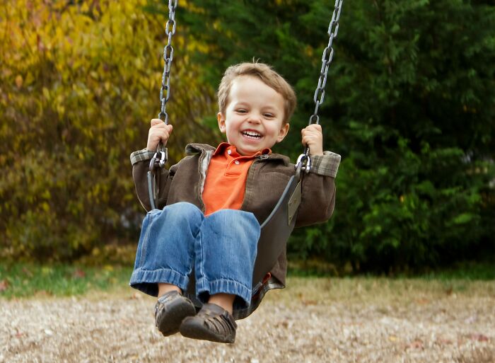 A child smiling on a swing, surrounded by autumn trees, capturing the essence of gradually disappeared pastimes.