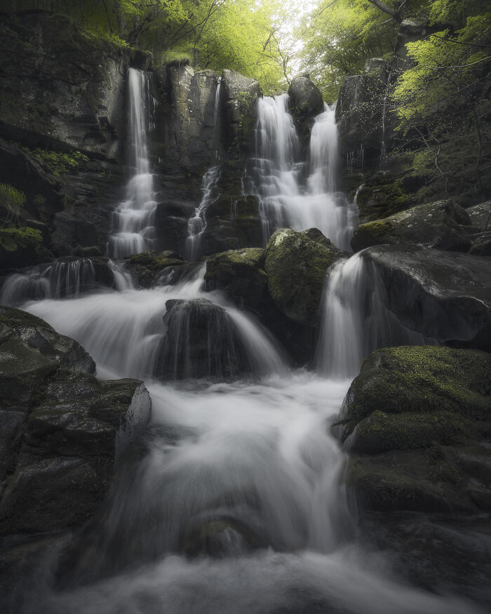 Stunning landscape photograph of a cascading waterfall surrounded by lush greenery.