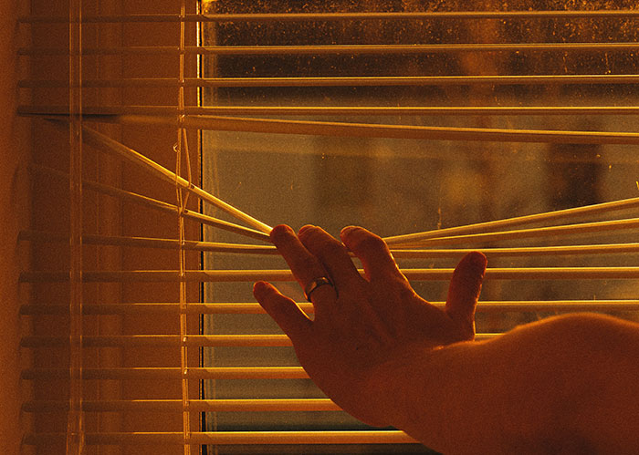 Hand opening window blinds, peering outside, related to unhinged neighbor pointing cameras. Hand opening window blinds, peering outside, related to unhinged neighbor pointing cameras.