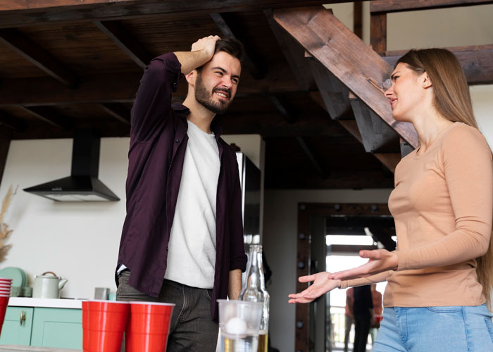 A couple arguing in a kitchen, red party cups on counter, echoing nightclub-like disturbance.