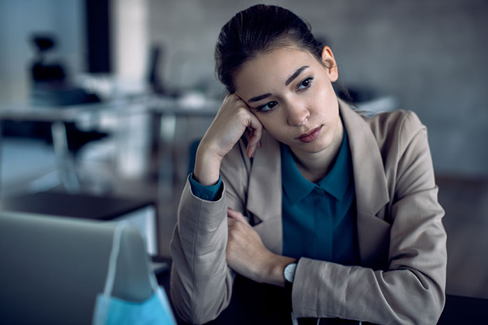 A woman in an office setting looks concerned, illustrating exclusion at work.