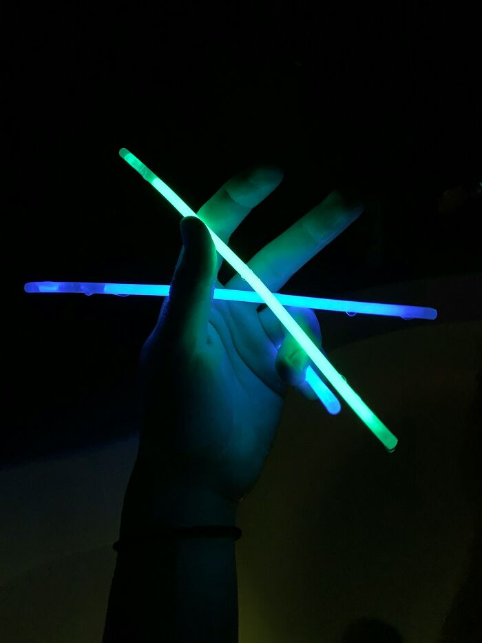 A hand holding glowing sticks, showcasing weird things doctors remove from bodies.