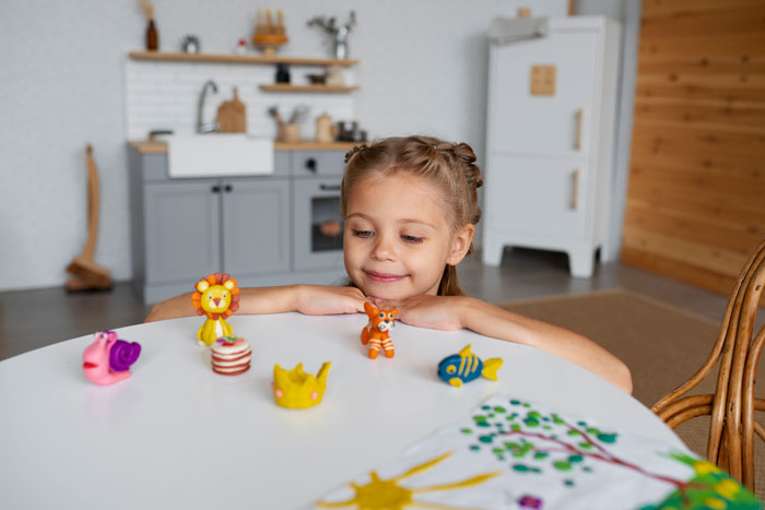 Young girl with toys at a table, representing aunt's response to sticky-fingers niece and stolen trinkets story.