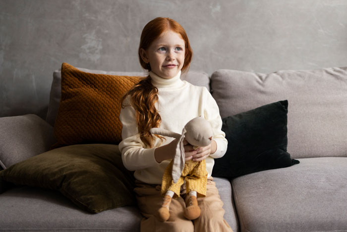 Child holding a doll on a sofa, related to a customized toy for a "Golden Child.