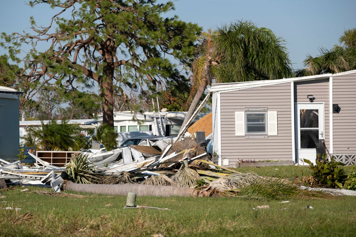 Hurricane aftermath with damaged home and fallen trees, illustrating destruction related to heirloom dolls.