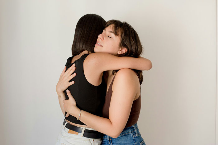 Two women embrace, symbolizing solidarity in coming out amidst homophobia.