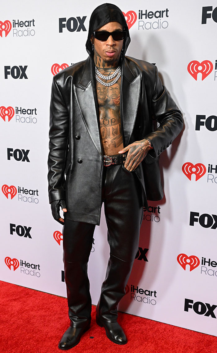 Man in black leather outfit and sunglasses at the 2025 iHeartRadio Music Awards red carpet.