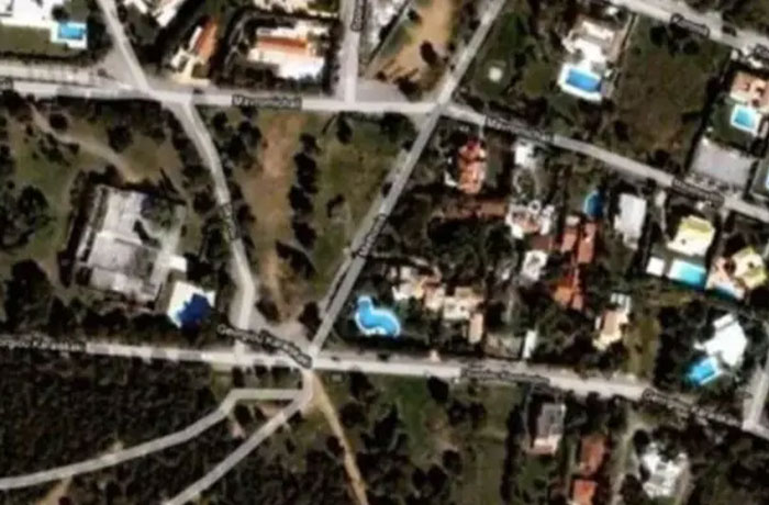 Google Earth view showing a landscape with intersecting roads and several bright blue swimming pools.
