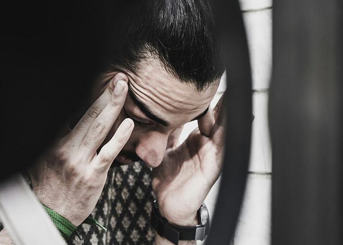 A person appears stressed, holding their head, possibly reflecting on traumatic childhood experiences.