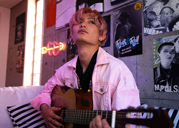 Person with a guitar in a room decorated with posters, embodying a unique style similar to mom groups.