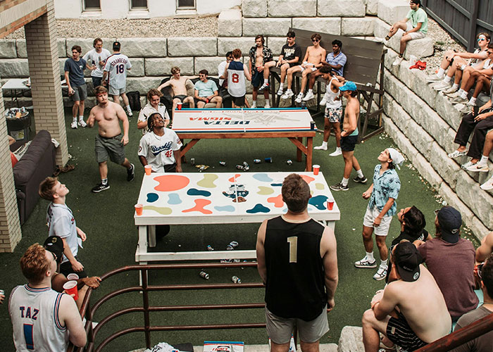 Group playing outdoor game, gathered around a colorful table, engaged circle, casual event atmosphere.