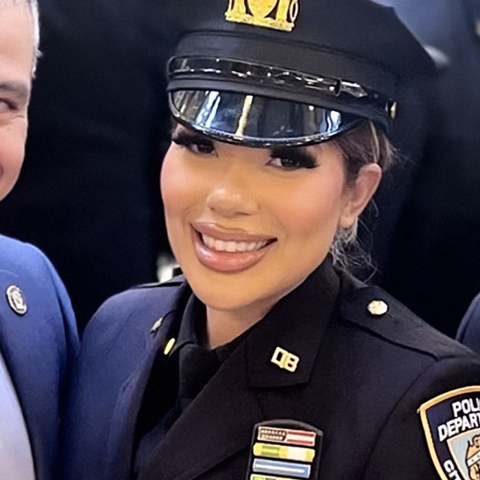 NYPD officer in uniform, smiling at an indoor event.