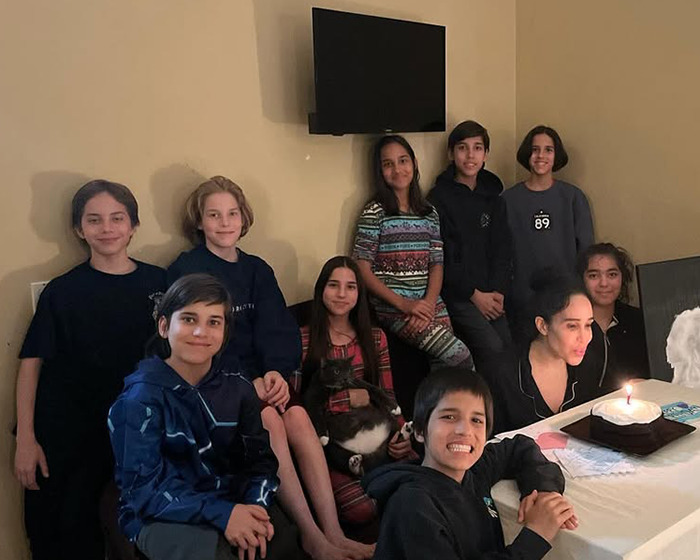Natalie Suleman with her children around a table, celebrating a birthday with a candle-lit cake.