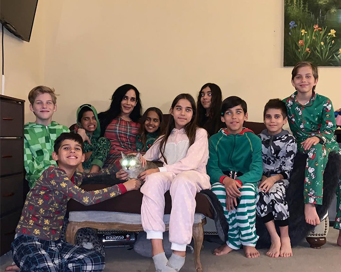 Natalie Suleman with her children in matching pajamas, sitting on a couch indoors, smiling at the camera.