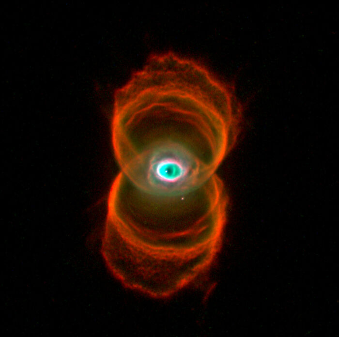 Colorful nebula in space resembling an eye with vibrant red and turquoise hues, set against a dark backdrop.