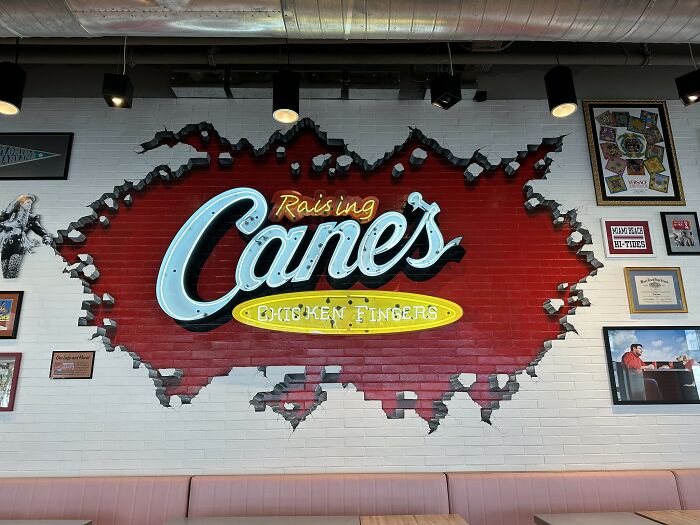 Raising Cane's wall sign with colorful restaurant decor and memorabilia.