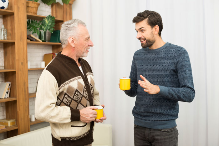 Two men in a cozy living room, holding yellow mugs, engaging in a conversation about family dynamics and stepsiblings. Two men in a cozy living room, holding yellow mugs, engaging in a conversation about family dynamics and stepsiblings.