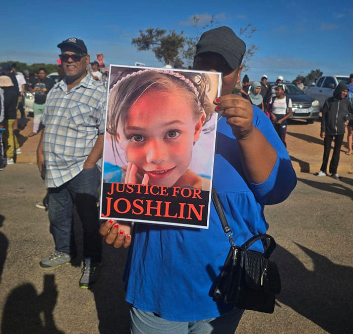 Protestor holds "Justice for Joshlin" sign amid crowd, highlighting case of daughter sold for $1,000.