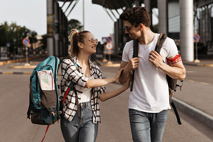 Young couple traveling with backpacks, sharing a moment of joy on a sunny day.