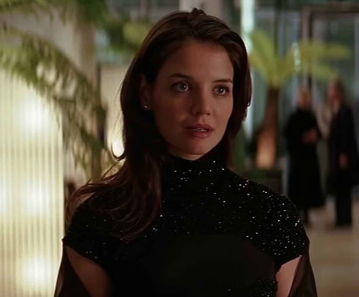 A woman in a sparkling black dress stands indoors, representing varied opinions on celebrity attraction.