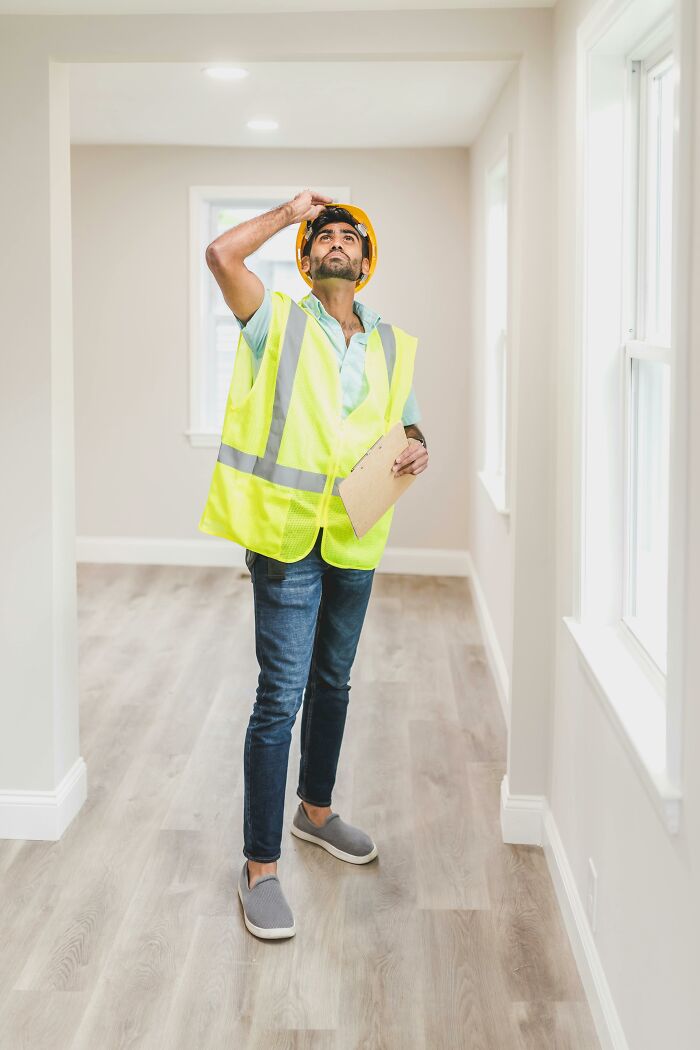 Inspector in a new home, wearing a safety vest and helmet, representing lessons from first-time home buyers.