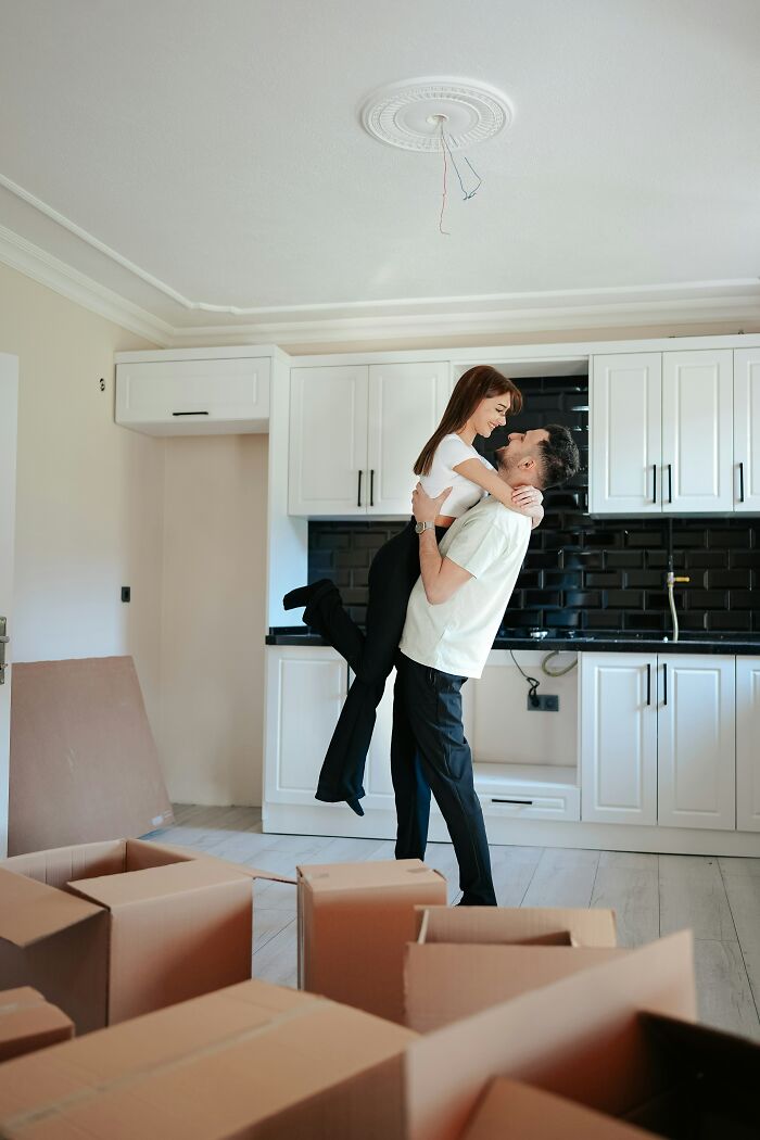 Couple celebrating in a new kitchen surrounded by moving boxes, symbolizing lessons learned by first-time home buyers.