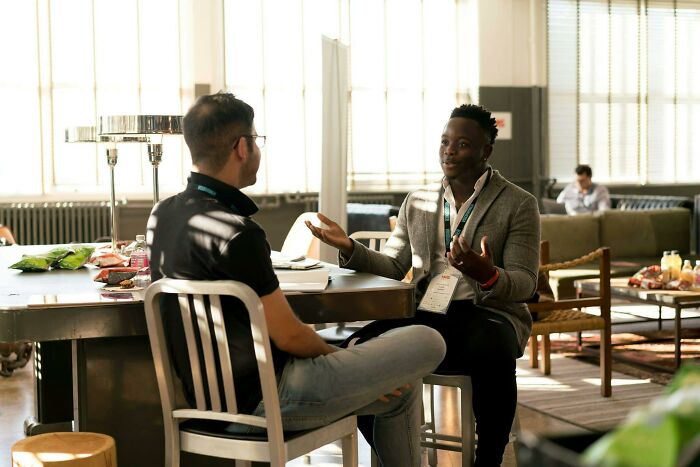 Two people having a serious discussion in an office setting with snacks on the table.