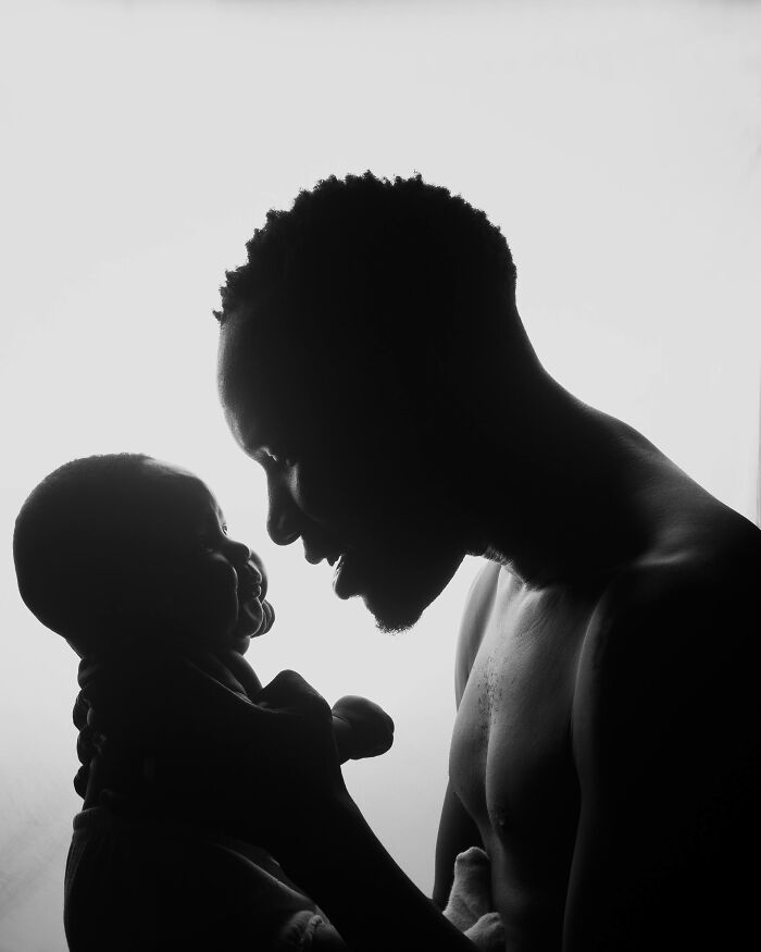 A person smiles at a baby in a silhouette, conveying a tender moment.