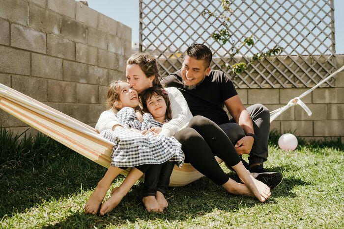 Family enjoying time together on a hammock in the backyard, illustrating lifestyle choices related to having kids.