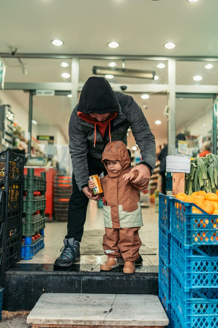 Adult and child in a market, surrounded by crates of oranges; illustrates decision-making about having kids.