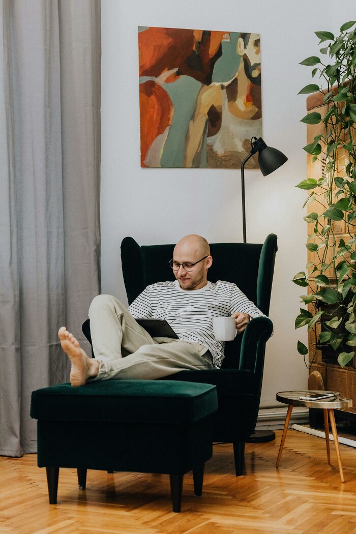 Man in striped shirt relaxing on a chair, reading with a mug, symbolizing deciding to never have kids.