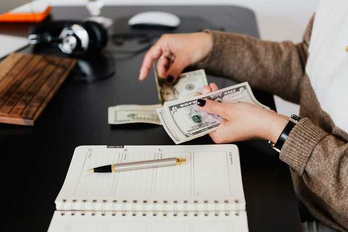 A person at a desk counting money with a notebook open, reflecting considerations for life decisions.