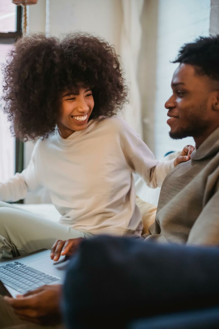 Two colleagues sharing a laugh by a laptop, capturing a lighthearted work moment.