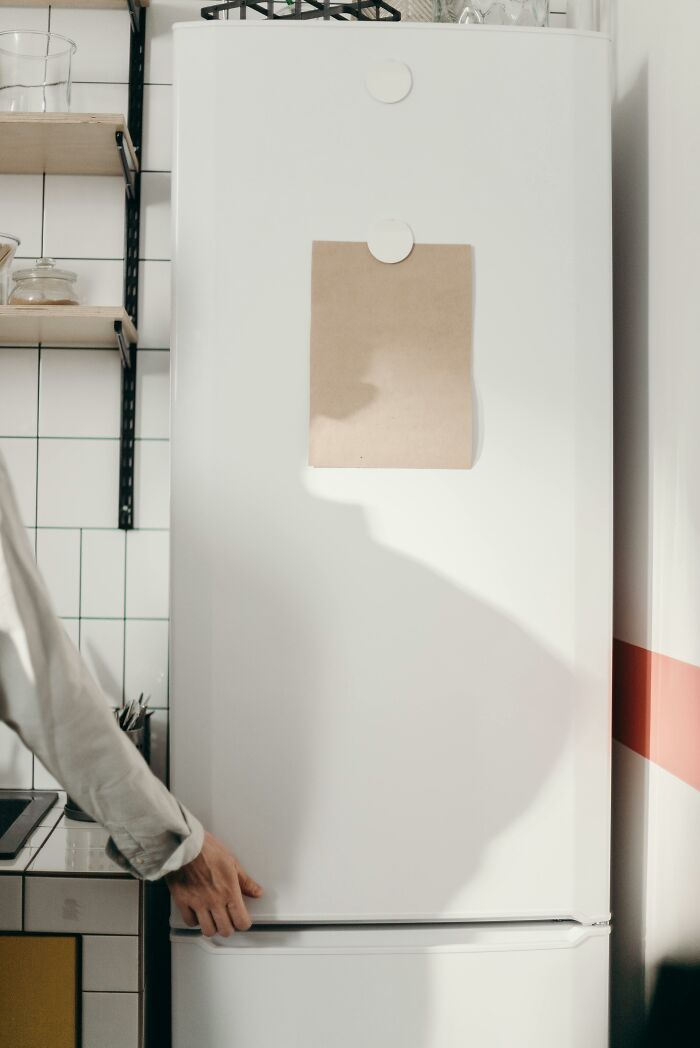 Person opening a white refrigerator in a kitchen, illustrating unprofessional things seen at work.