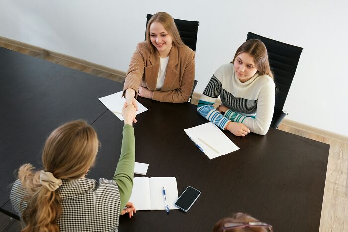 People discussing work at a table with notebooks and a smartphone in a professional setting.