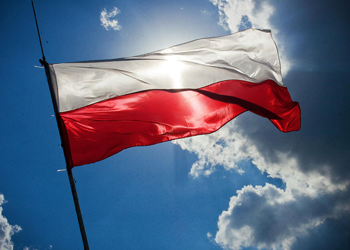 Polish flag waving in the sky, representing country humor discussions.