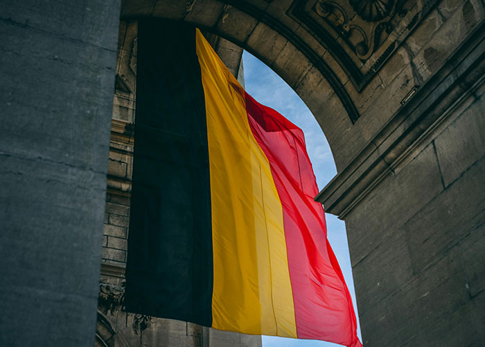 Belgian flag under an arch, representing a country often made fun of in global humor discussions.