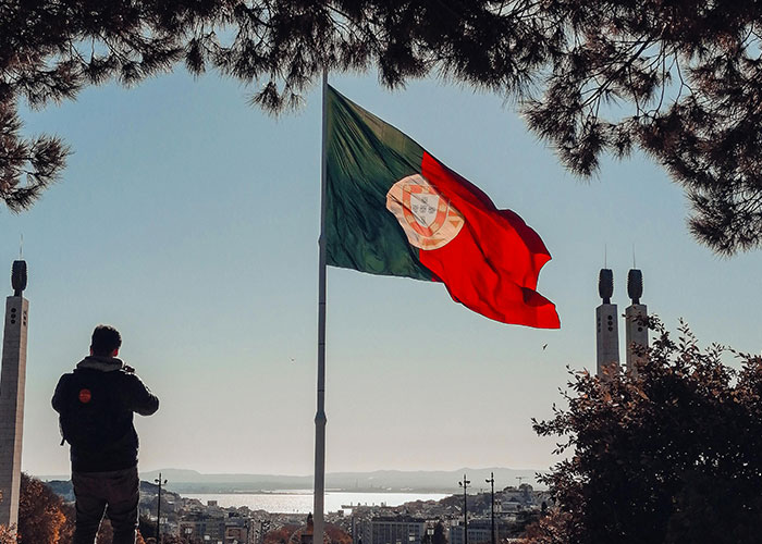 Man photographing a Portuguese flag overlooking the city.