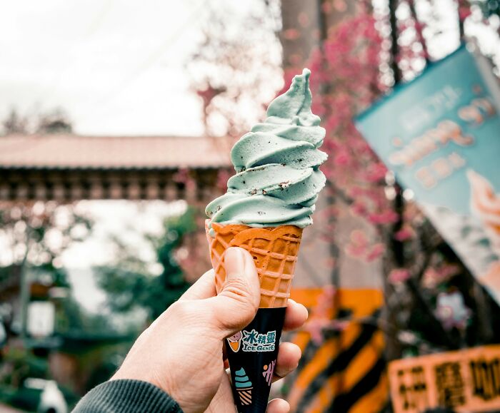 Hand holding a mint ice cream cone outdoors, showcasing a treat that gets more hate than it deserves.