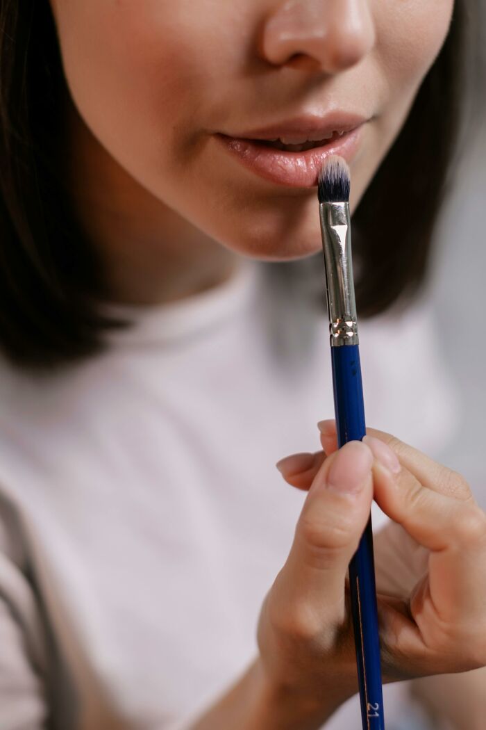 Person applying makeup with a brush, highlighting beauty standards and trends.