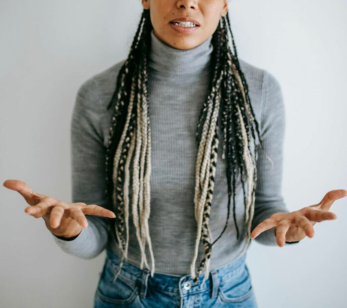 Person gesturing with hands in a gray turtleneck, representing a wedding "red flag" discussion.
