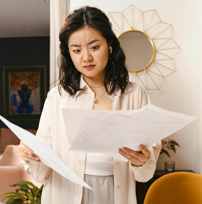 Woman looking confused while reviewing papers, illustrating worst job bonus experiences.