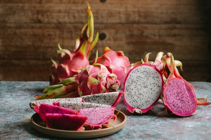 Unusual foods: sliced and whole dragon fruit on a rustic table.
