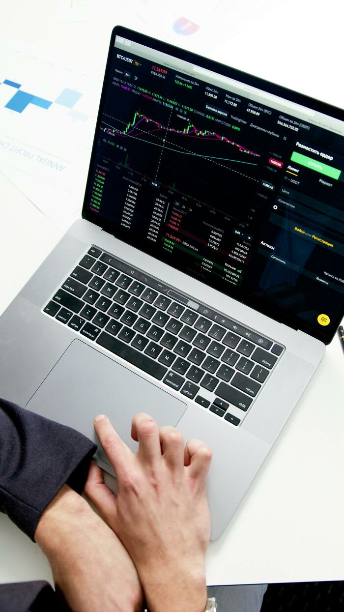 Person using a laptop displaying a trading platform, demonstrating earning money easily through investment.