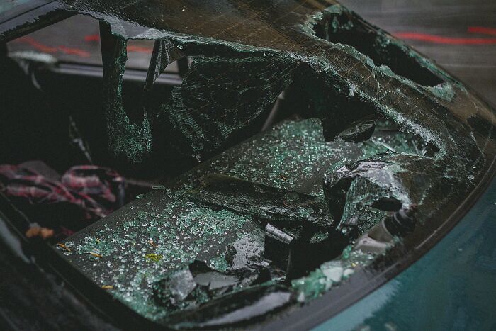 Shattered car windshield with glass fragments scattered after an impact, highlighting themes of patients' regrets.