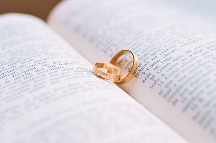 Wedding rings resting on a book, representing potential wedding red flags.