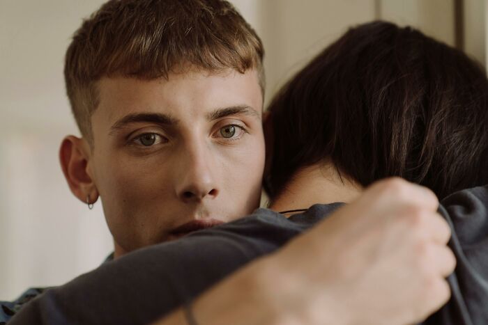 A person hugging another with an unsettled expression, illustrating a moment of crossing personal boundaries.