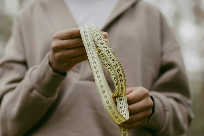 Person holding a measuring tape, comparing imperial and metric units.